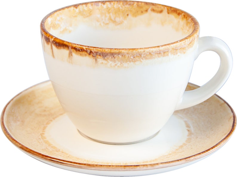 May include: A white ceramic coffee cup with a brown rim and a brown stain around the top. The cup is sitting on a matching saucer.