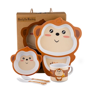 May include: A brown and white monkey-shaped plate with a smaller brown and white monkey-shaped bowl, a white mug with a brown monkey design, and two brown and white utensils. The box says "Monty the Monkey".