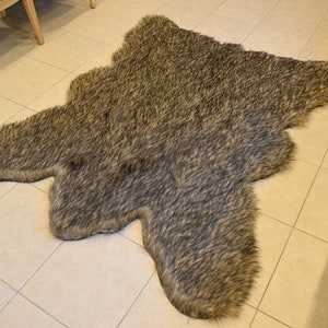May include: A faux fur rug in a naturalistic shape, featuring a blend of brown and gray tones. The rug is placed on a tiled floor, offering a soft, textured accent for home decor.