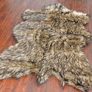 May include: A brown and black faux fur rug with a shaggy texture. The rug is shaped like a hide and has a natural, rustic look.