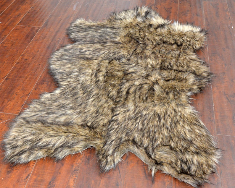 May include: A brown and black faux fur rug with a shaggy texture. The rug is shaped like a hide and has a natural, rustic look.