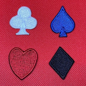 Puede incluir: Cuatro parches bordados de palos de cartas: un trébol blanco, una pica azul, un corazón rojo y un diamante negro. Los parches están sobre un fondo de tela roja texturizada. Estos parches son ideales para añadir un toque único a la ropa o accesorios.
