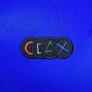 Pode incluir: Quatro patches circulares pretos e brancos com diferentes símbolos coloridos no centro. Os símbolos são um círculo, um quadrado, um triângulo e um X. Os patches estão dispostos em uma linha da esquerda para a direita.