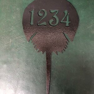 Pu&ograve; includere: Un cartello di numero civico in metallo nero a forma di ferro di cavallo con il numero 1234 al centro.