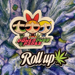 May include: A sticker featuring the Powerpuff Girls cartoon characters with a marijuana leaf and the text "The Powerpuff Girls" and "Roll Up" with a marijuana leaf.