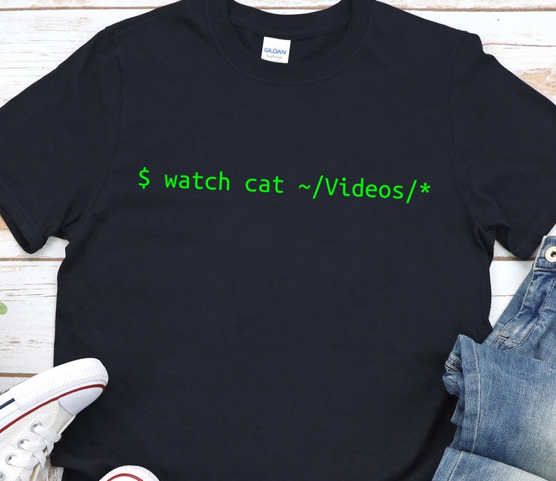 Puede incluir: Una camiseta negra con texto verde que dice "$ watch cat ~/Videos/*"