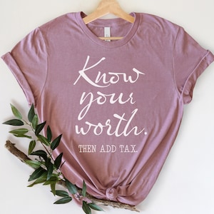 Op de afbeelding: Een mauve t-shirt met de tekst "Know your worth. Then add tax." in wit gedrukt.