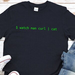 May include: A dark blue t-shirt with the text "$ watch man curl | cat" printed in green.