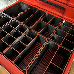 May include: Red toolbox with black and red dividers. The dividers create multiple compartments for organising small items.