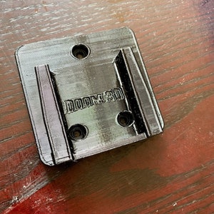 Pu&ograve; includere: Supporto da parete in plastica nera con la scritta "DOOM 3D" stampata su di esso.