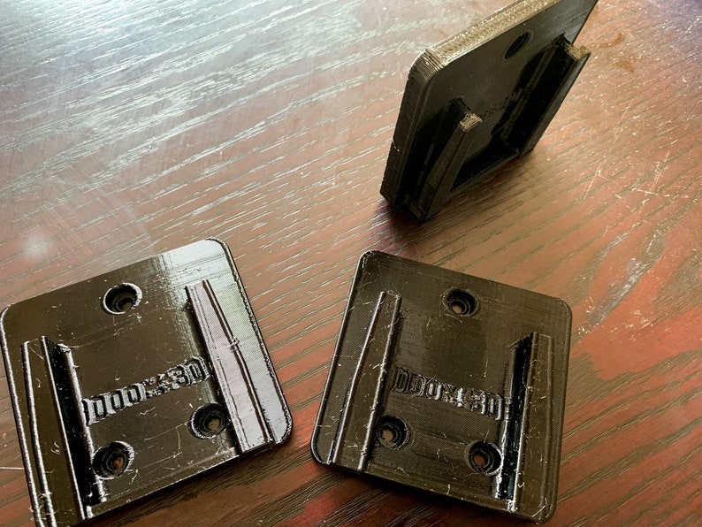 Pu&ograve; includere: Tre supporti a parete in plastica nera con la scritta "DORO3D" stampata su di essi.