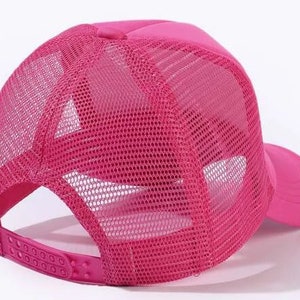 May include: A pink mesh trucker hat with a solid pink front panel and a mesh back panel. The hat has a curved brim and an adjustable strap.
