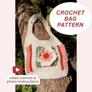 Op de afbeelding: Crèmekleurige gehaakte tas met een bloemenontwerp. De tas heeft een grote bloem in het midden, met roze en groene accenten. De tekst "CROCHET BAG PATTERN" staat in een witte cirkel. Inclusief video tutorial en foto-instructies.