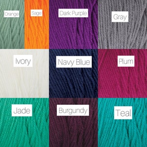 Peut inclure: Une collection de pelotes de laine de diff&eacute;rentes couleurs, notamment orange, sauge, violet fonc&eacute;, gris, ivoire, bleu marine, prune, jade, bordeaux et sarcelle.