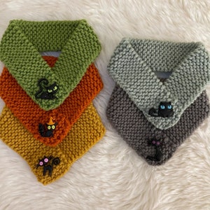 Peut inclure: Quatre tours de cou en tricot de couleur verte, orange, jaune et grise avec des appliques de chat noir. Les appliques de chat ont des expressions différentes et certaines ont des chapeaux de sorcière.