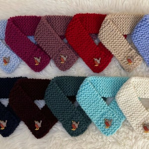 May include: A collection of ten knitted neck warmers in various colors, each featuring a small embroidered robin. The colors include navy blue, burgundy, teal, light blue, white, beige, red, mauve, and pink.