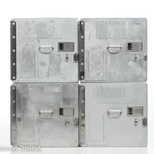 Puede incluir: Cuatro contenedores de almacenamiento de metal plateado con asas y cierres. Cada contenedor tiene la palabra "Britannia" impresa en la parte delantera.