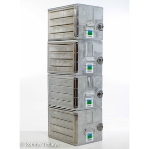 Puede incluir: Cuatro contenedores de almacenamiento de metal apilados, de estilo industrial. Cada contenedor es una caja rectangular con detalles acanalados horizontales en la parte delantera. Los contenedores son de color gris plateado con una pegatina "LEVEL" verde y azul.