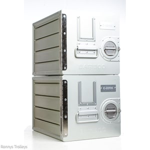 May include: Two stacked, silver-colored metal storage containers. Each container has a rectangular shape with a handle, a circular latch, and the word "BAMBOO" printed on the front. The containers are designed with a riveted construction and a side panel with horizontal slats.