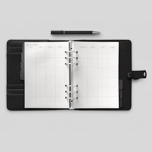 May include: A black leather bound monthly planner with silver rings and a white paper insert. The planner is open to a monthly calendar view with the days of the week labeled. The planner has a tab for each day of the week and a notes section.