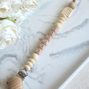 Beige colour silicone dummy chain with wooden safety stopper bead, natural wood clasp,  with mahogany letter beads. made on chocolate brown nylon cord.