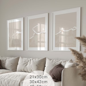 May include: Three framed prints with white calligraphy on a beige background. The prints are hanging on a light gray wall above a white sofa. The sofa has brown throw pillows. The prints are available in various sizes: 21x30cm, 30x42cm, 40x50cm, 50x70cm, 61x91cm.