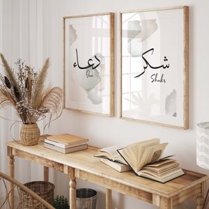 May include: Two framed prints with watercolor backgrounds and Arabic calligraphy. The left print says "Dua" and the right print says "Shukr".