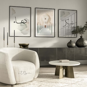 May include: Three framed prints on a white wall. The center print shows a hallway with arched doorways and columns. The left print features the Arabic word "Dua" in black calligraphy with a watercolor background. The right print features the Arabic word "Shukr" in black calligraphy with a watercolor background.