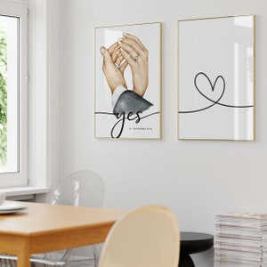 May include: Two wedding-themed prints. The first print features a watercolor illustration of two hands holding each other with a ring on one finger. The text "yes" is written in black cursive with the date "15. NOVEMBER 2018" below. The second print features a simple black line drawing of a heart.