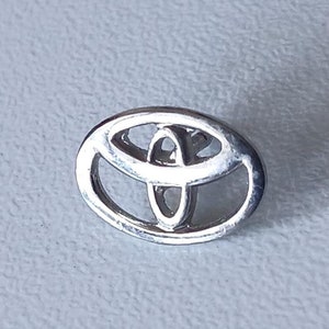 May include: A silver Toyota logo with a stylised oval and overlapping circles.