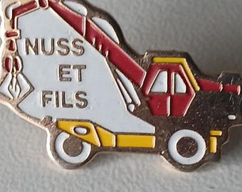 Rare Collector’s Pin: NUSS ET FILS Excavator on Trailer – Brand Badge for Construction Enthusiasts