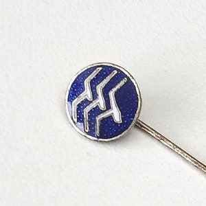 Può includere: Uno spillo d'argento con un cerchio di smalto blu che presenta un design a onda stilizzato bianco.