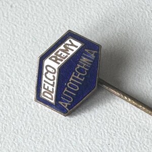 Peut inclure: Une épingle vintage Delco Remy Autotechnia. L'épingle présente un emblème hexagonal bleu et blanc avec le nom de la marque et du texte. L'épingle a une longue et fine tige métallique. Il s'agit probablement d'un objet de collection.