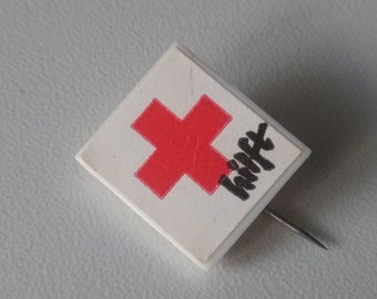 Red Cross helps: plastic pin 1970s