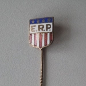 Peut inclure: Une épingle dorée avec un motif en forme de bouclier. Le bouclier est bleu avec des étoiles blanches et des rayures rouges et blanches. Les lettres "E.R.P." sont imprimées en noir sur le bouclier.