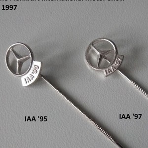 以下が含まれることがあります： メルセデス・ベンツの星型ロゴと「IAA '95」と「IAA '97」の文字が刻まれた銀色のピンが2つ。