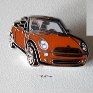 Op de afbeelding: Oranje geëmailleerde pin van een BMW Mini cabriolet. De pin is 27 mm x 17 mm en heeft de tekst "BMW MINI Cabriolet Pin emailliert frühe 2000er" en "BMW MINI convertible pin enameled early 2000s".
