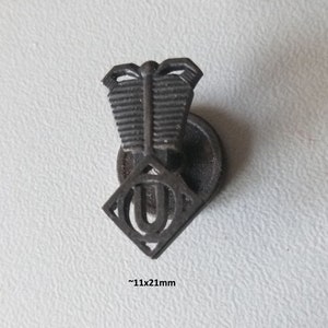 Może przedstawiać: Czarny metalowy guzik śrubowy z motywem cylindra dwusuwowego i literą "U". Guzik jest wytłoczony napisem "1950er Jahre oder älter" (lata 50. XX wieku lub starszy).