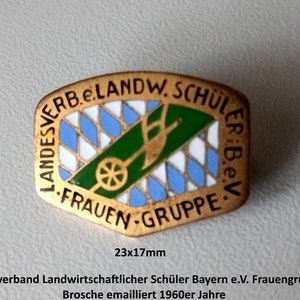 Könnte beinhalten: Eine goldfarbene Emaille-Anstecknadel mit einem blau-weiß karierten Design, einer grünen Schubkarre und dem Text "Landesverband Landwirtschaftlicher Schüler Bayern e.V. Frauen Gruppe" in deutscher Sprache. Die Anstecknadel ist 23 mm x 17 mm groß.
