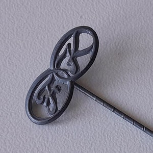 以下が含まれることがあります： 二重ループのデザインで、文字「SF」が絡み合った銀色のピン。ピンは長く、細く、ねじれたシャフトになっています。