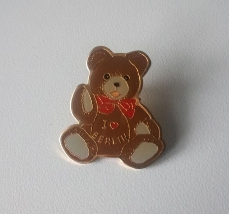 Puede incluir: Un oso de peluche marr&oacute;n con una pajarita roja y un pin dorado que dice "Amo Berl&iacute;n".