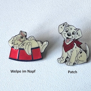 Könnte beinhalten: Zwei Emaille-Anstecknadeln mit Dalmatiner-Welpen. Eine Nadel zeigt einen Welpen, der sich in einer roten Schüssel ausruht, die andere einen Welpen mit rotem Halstuch. Die Texte "Welpe im Napf" und "Patch" stehen darunter.