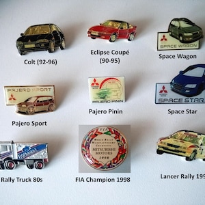May include: A collection of ten vintage car badges featuring various Mitsubishi models, including the Colt, Eclipse, Space Wagon, Space Star, Pajero Sport, Pajero Pinin, and Lancer Rally. The badges are made of metal and feature detailed designs of the cars.