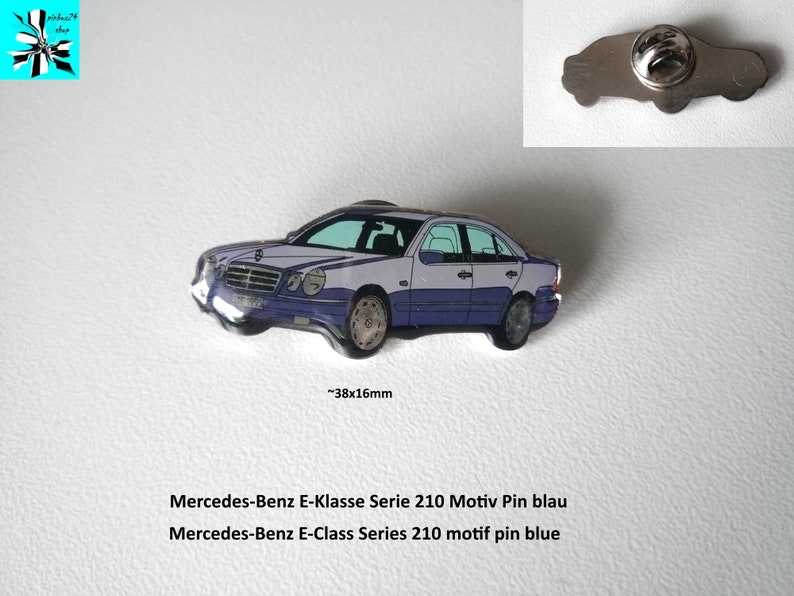 May include: A blue and silver enamel pin of a Mercedes-Benz E-Class Series 210 car. The pin is approximately 1.5 inches wide and 0.6 inches tall. The text "Mercedes-Benz E-Klasse Serie 210 Motiv Pin blau" and "Mercedes-Benz E-Class Series 210 motif pin blue" is printed below the pin.