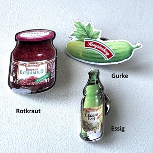 May include: Three fridge magnets with food product designs. One shows a jar of Rotessa Extramild red cabbage, another a cucumber with the Hengstenberg logo, and the third a bottle of 13 Kräuter Essig.