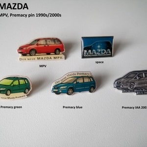 Puede incluir: Una colección de cuatro pines de coches Mazda. Los pines muestran un Mazda MPV rojo, un Mazda Premacy verde, un Mazda Premacy azul y un Mazda Premacy plateado. Los pines están todos en buen estado y tienen el texto "Der neue Mazda MPV" y "Der neue Mazda Premacy" en ellos.