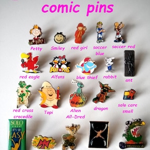 May include: A collection of colorful enamel pins featuring cartoon characters, animals, and symbols. The pins are arranged in rows on a white background. Some of the pins include a red eagle, a blue thief, a red cross crocodile, a red falcon, a billy goat, and a monster.