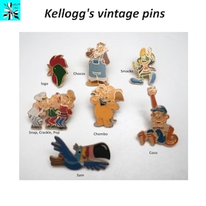 Könnte beinhalten: Eine Sammlung von Vintage-Anstecknadeln mit Kellogg's-Müslifiguren. Die Anstecknadeln zeigen Figuren wie Snap, Crackle, Pop, Coco, Sam, Chocos, Chombo und Smacks. Die Anstecknadeln sind aus Metall und haben eine goldene Oberfläche.