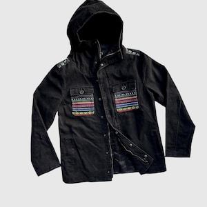 May include: A black hooded jacket with a zipper closure and two flap pockets. The pockets have colorful embroidered details.