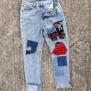 May include: Light blue denim jeans with multiple patches of different fabrics and patterns. The patches include a red and white paisley pattern, a blue and white geometric pattern, and a blue and white floral pattern.
